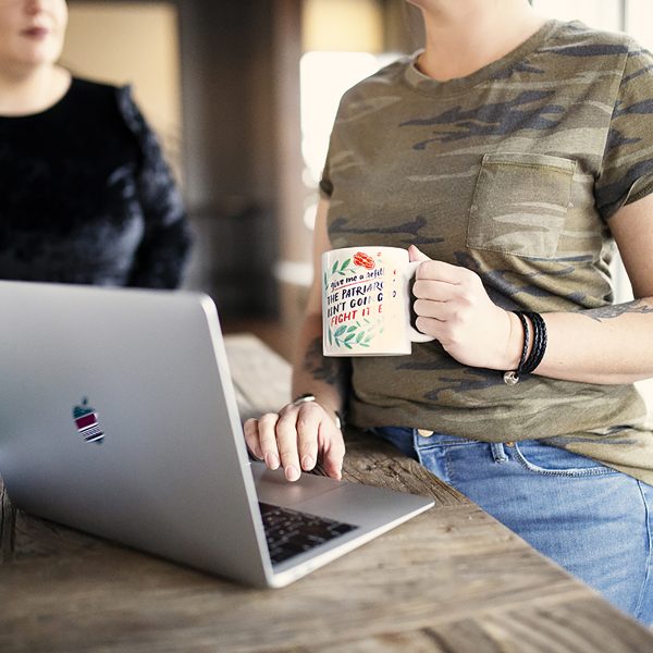 holding coffee mug with laptop